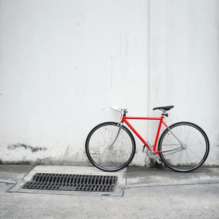 Red bicycle leaning on white wallの写真素材