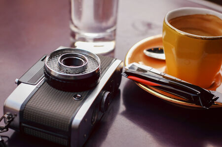 Cup of coffee and retro film camera in cafeの写真素材