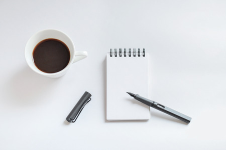Coffee cup, spiral notebook and pen on white background - taken in natural light with strong shadow to create realistic indoor moodの写真素材