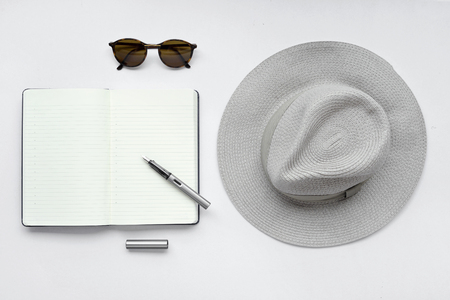 Sunglasses, notebook, pen, and hat, on white background - taken in natural light with strong shodow to create realistic indoor moodの写真素材