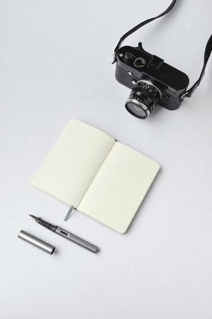 Notebook, pen, and camera, on white background - taken in natural light with strong shodow to create realistic indoor moodの写真素材