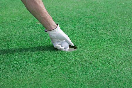 Taking a golf ball out of a holeの写真素材