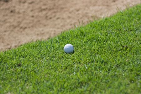 Golf ball that is close to the edge of the sandの写真素材
