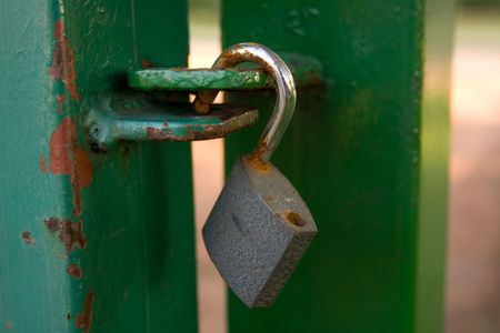 Open pad lock on a green metal gateの写真素材