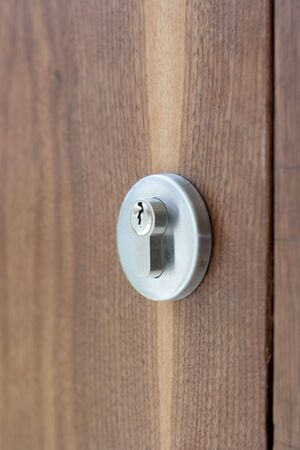 This is a silver door lock on a wooden doorの写真素材