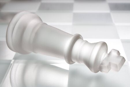 Defeated king on a chess boardの写真素材