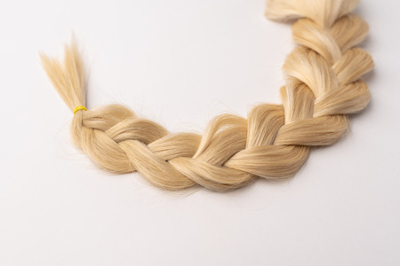 Human, natural light blond hair tress on white isolated background. An example of a fashionable hairstyle for a poster or an hairdressing website.の写真素材