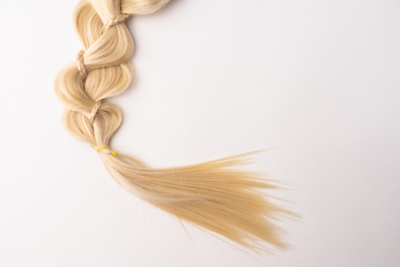 Human, natural light blond hair tress on white isolated background. An example of a fashionable hairstyle for a poster or an hairdressing website.の写真素材