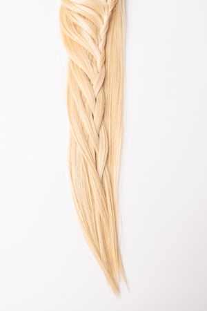 Human, natural light blond hair tress on white isolated background. An example of a fashionable hairstyle for a poster or an hairdressing website.の写真素材