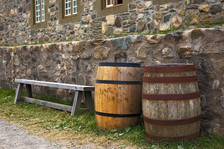A bench and two barrels along side stone wallsの写真素材