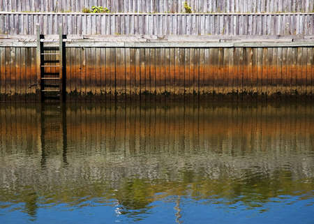 Wooden Dock & Ladder with a blue sky relecting in the waterの写真素材