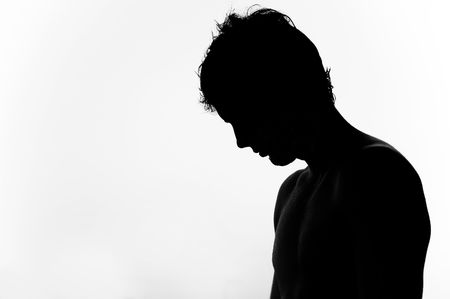 Silouhette of a man with the head tilted down, inspiring sadness or preocupationの写真素材