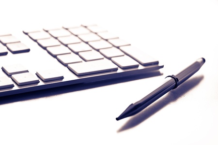 Shot of a white keyboard and a silver pen. Shallow depth of field. Great background for business designs.の写真素材