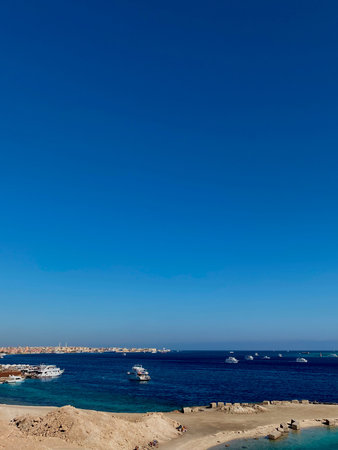 A panoramic view captures numerous yachts and vessels anchored in the azure waters, with a distant...