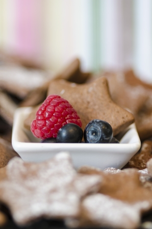 Bowl with fresh raspberry  blueberries and a tasty freshly baked star cookie in a traditional Christmas seasonalの写真素材