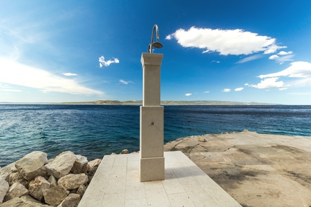 shower on a rocky beach, blue sea landscape in the backgroundの写真素材