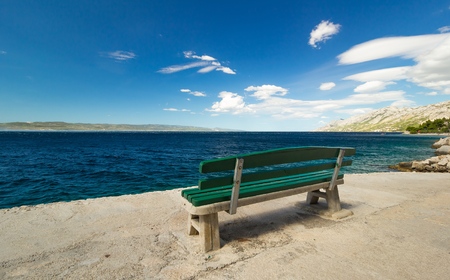 Empty green bench by the sea, beautiful landscapeの写真素材
