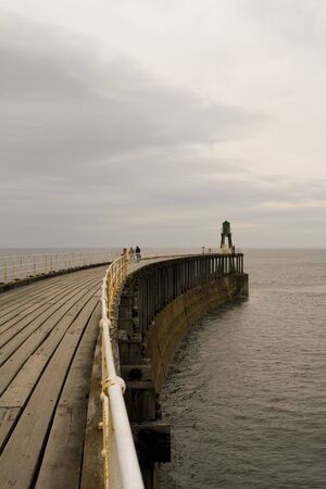 View of Whitby Harbour, overcast sky. Boardwalk out to sea.の写真素材
