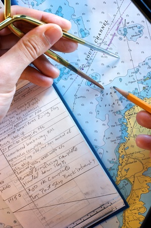 Person plots a path on a chart, with a notebook visible の写真素材