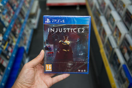 Bratislava, Slovakia, june 15, 2017: Man holding Injustice 2 videogame on Playstation 4 console in storeのeditorial素材