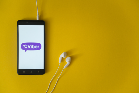 Foto de Los Angeles, USA, october 23, 2017: Viber logo on smartphone screen and earphones plugged in on yellow background. - Imagen libre de derechos