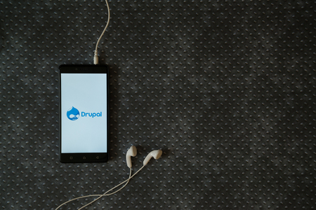 Los Angeles, USA, october 23, 2017: Drupal logo on smartphone screen and earphones plugged in on metal plate background.のeditorial素材