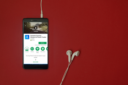 Los Angeles, January 11, 2018: Smartphone with Runtastic running application in google play store on red background with earphones plugged in and copy spaceのeditorial素材