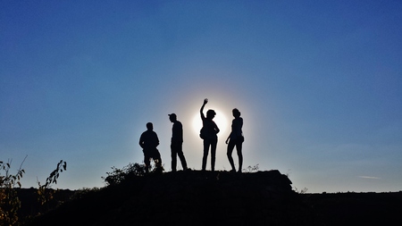 Four people are standing in front of the sun lightの写真素材