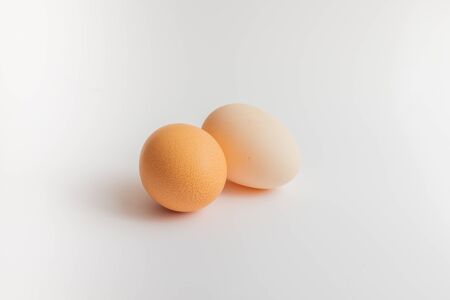One is brown and the other is white, two organic eggs on the white backgroundの写真素材