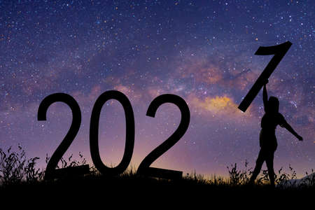 Silhouette walking women holding number 1 on the hill while celebrating 2021 years in the milky way background.の写真素材