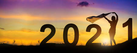 Silhouette enjoying women flapping a thin fabric on the hill while celebrating 2021 years in the twilight background.の写真素材