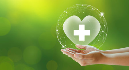 Hand offer hospital heart with white cross on green background. Family life insurance, Medical care insurance, and Business healthy concepts.の写真素材