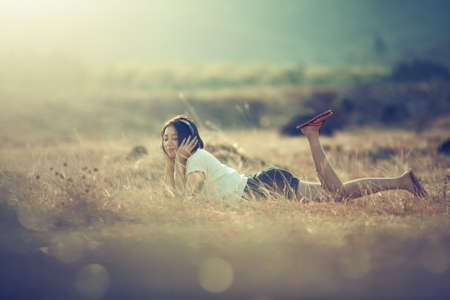 Young asian girl listening music by headphone in garden. Happy and smiling while listening music in...