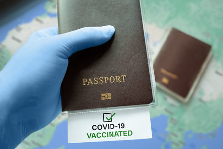 Hand in medical gloves holding passportの写真素材