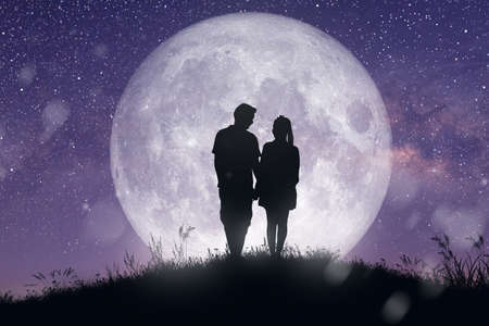 Silhouette at night landscape of couple or lover dancing and singing on the mountain with Milky way background over the full moon.の写真素材