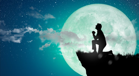 Silhouette at night landscape. A man is praying God on the cliff over the full moon.の写真素材