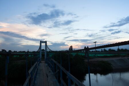 During the twilight sky. A small rope bridge made of wood and wire slings silhouette.の写真素材