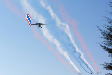 PRACHUAPKHIRIKHAN THAILAND - January 9, 2016: The plane's color smoke emissions. And dragging the flag in the air on Children's Day on JAN 9, 2016 in PRACHUAPKHIRIKHAN, THAILAND.のeditorial素材