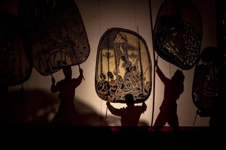 RATCHABURI THAILAND - APRIL 14, 2015: The Cowskin shows a man holding a stencil pattern. Moving Cowskin the light to shadow play. The musical atmosphere and read a poem composed.のeditorial素材