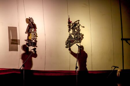 RATCHABURI THAILAND - APRIL 14, 2015: The Cowskin shows a man holding a stencil pattern. Moving Cowskin the light to shadow play. The musical atmosphere and read a poem composed.のeditorial素材