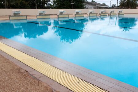 blue water wave in swimming pool reflects with sunlight , blue tile ceramic to swimming race and...