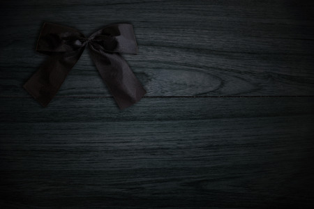 Black bow on black wood plate. Symbol of sadness and mourning. Low key.の写真素材
