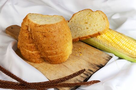 bread made from corn on the white fabric. Slices of corn bread laying on a chopping Board and Sweet corn cobsの写真素材