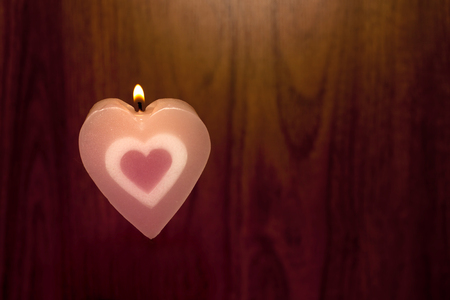 Candles shape heart pink color were lit on wood background. Love symbol for Valentine's day concept.の写真素材