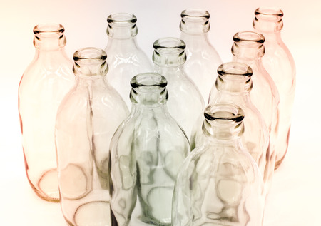 Detail of glass bottles on white background. Hint of red and blue color filterの写真素材