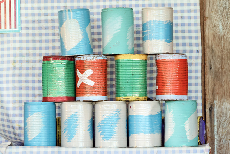Tin cans for throwing balls at them on blue and white striped backgroundの写真素材