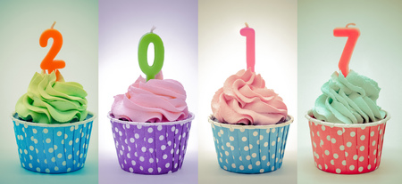 Retro color / Chocolate cupcakes in rows with candles 2017 on white background