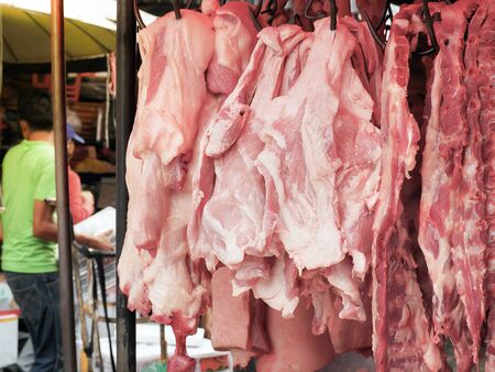 Fresh pork fillet hanging on display for sale at the butcher shop.