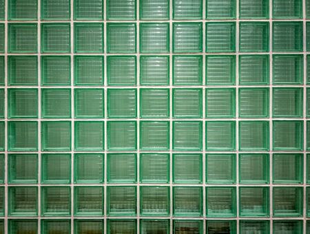 Green glass wall background. Wall of shiny tiled glass blocks in green.