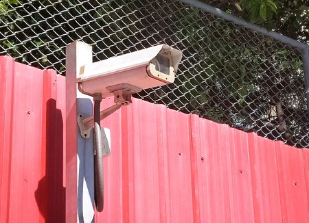 CCTV camera security on the red wall in the car parking. (security, safety, technology)